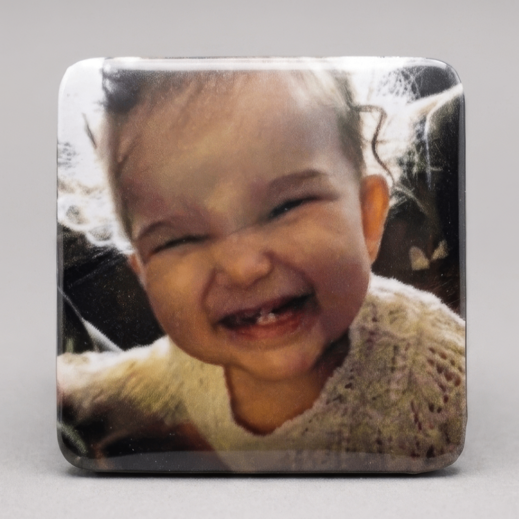 Ímã com foto de bebê rindo mostrando o primeiro dentinho
