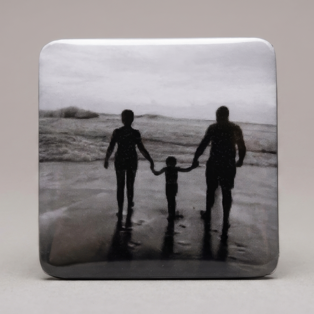 Ímã com foto em preto e branco de família de mãos dadas caminhando na beira do mar